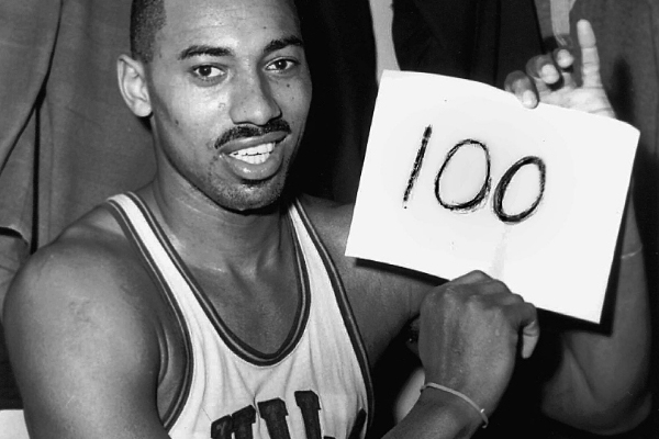 Wilt Chamberlain holding a paper with “100” written on it.